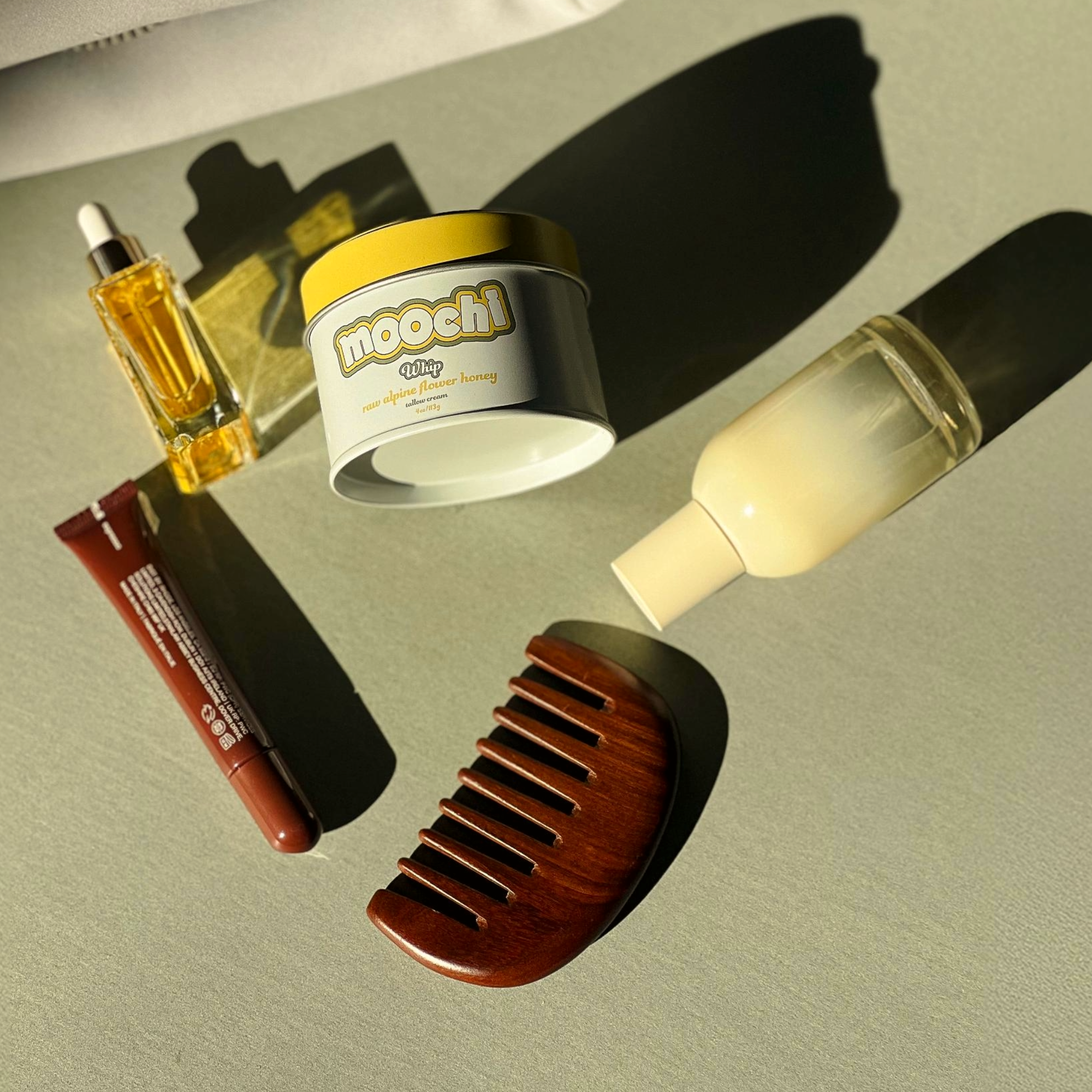 Moochi Raw Alpine Honey tallow cream tin styled with natural skincare and beauty essentials in warm sunlight
